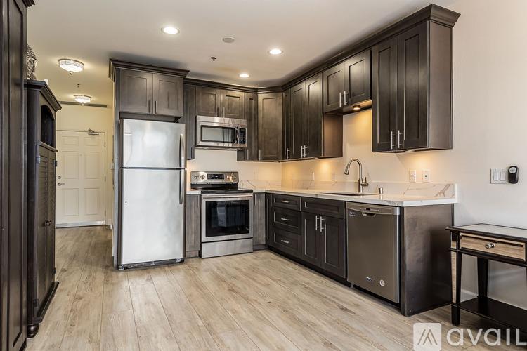 A modern kitchen with dark wood cabinets and stainless steel appliances.