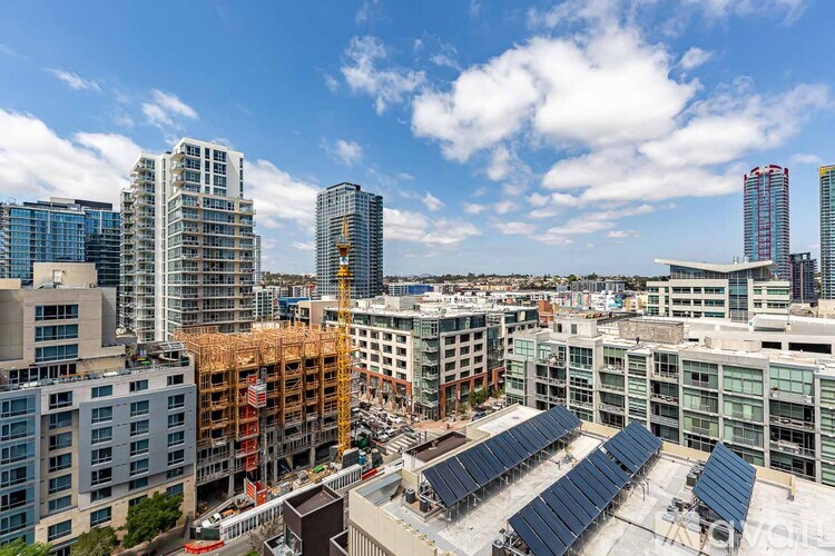 A cityscape with a construction site in the foreground and several buildings in the background.