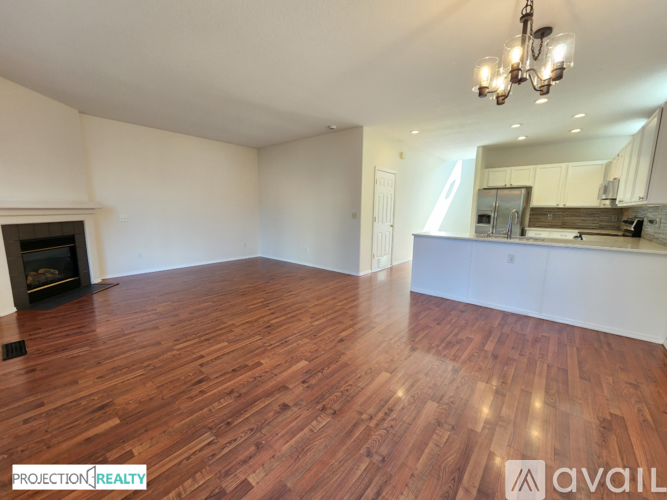 A spacious room with wooden flooring and a fireplace.