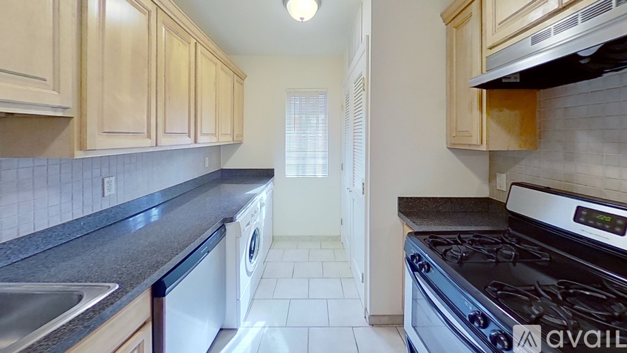 A kitchen with a stove, sink, and cabinets.