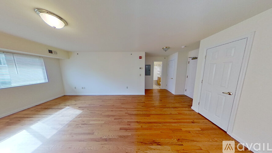 A spacious room with wooden flooring and white walls.