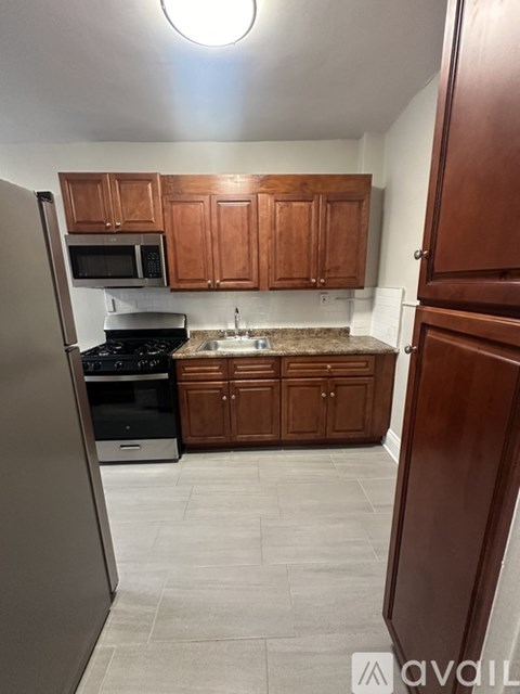 A kitchen with wooden cabinets and a stainless steel refrigerator.