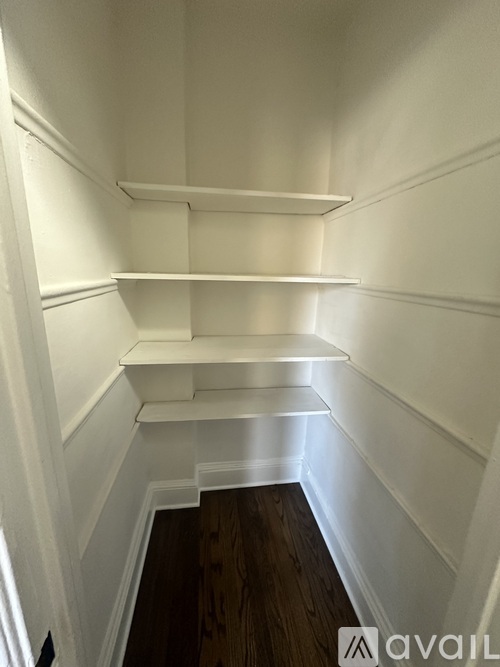 A white empty room with wooden floors and white walls.