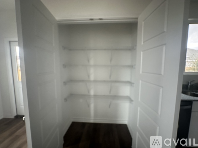 A white pantry with a wooden floor and white shelves.