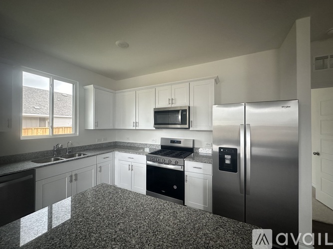 A kitchen with white cabinets and a stainless steel refrigerator.