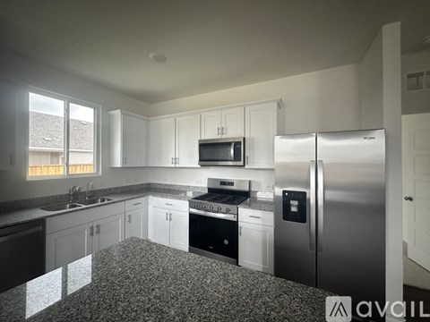 A kitchen with white cabinets and a stainless steel refrigerator.