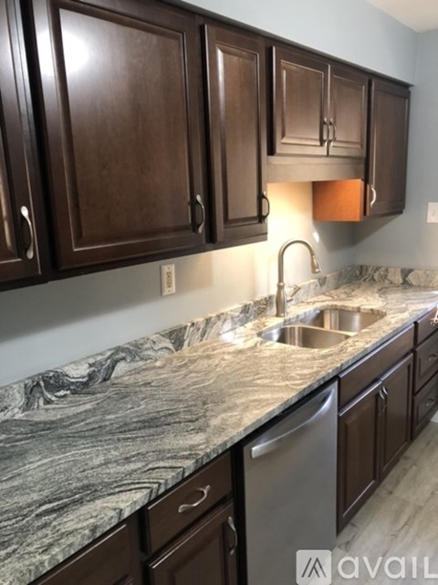 A kitchen with brown cabinets and a marble countertop.