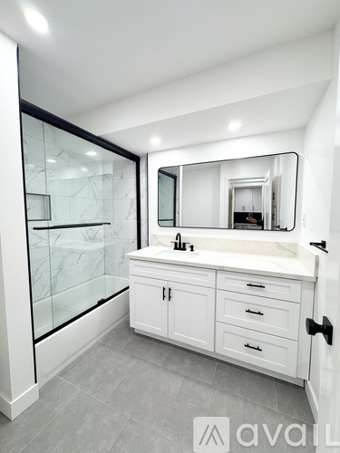 A bathroom with a marble shower and a white vanity.