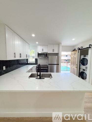 A kitchen with white cabinets and a marble countertop.