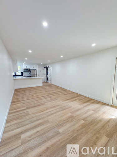 A spacious room with wooden flooring and white walls.
