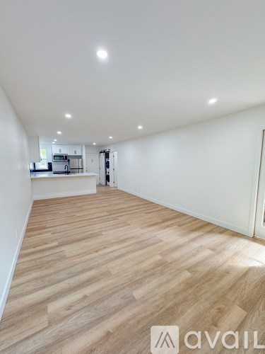 A spacious room with wooden flooring and white walls.