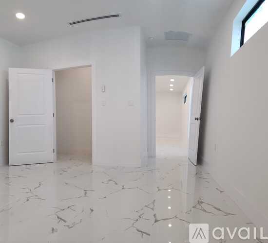 A spacious room with marble flooring and white walls.