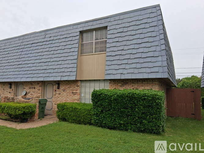 A house with a grey roof and a green trash bin.
