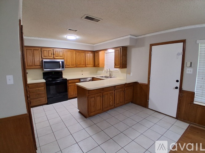 A kitchen with wooden cabinets and white tiled flooring.