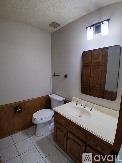 A bathroom with a toilet, sink, and mirror.