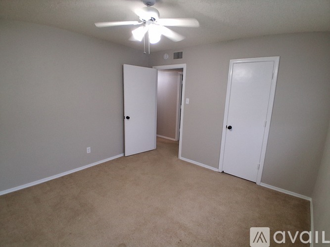 A room with a carpeted floor and two doors.