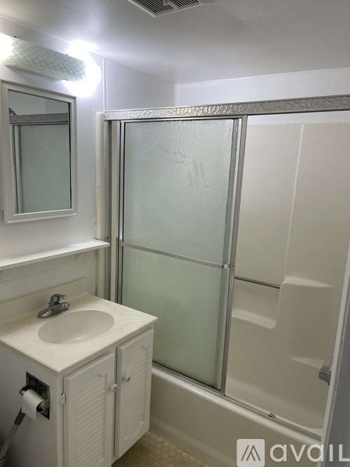 A white bathroom with a sink, mirror, and shower.