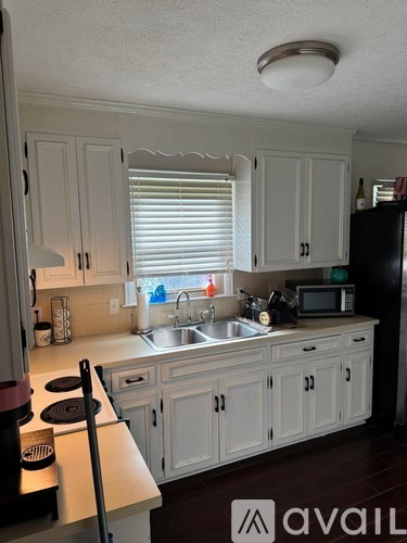 A kitchen with white cabinets and a black refrigerator.