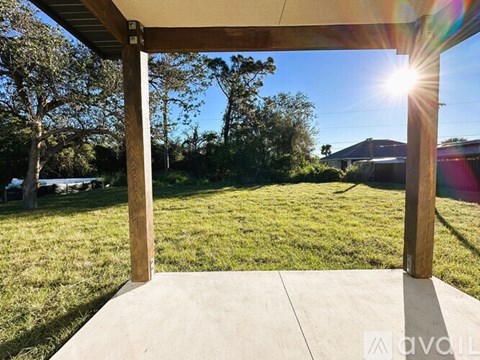 A wooden pergola over a concrete patio with a sunny backyard.