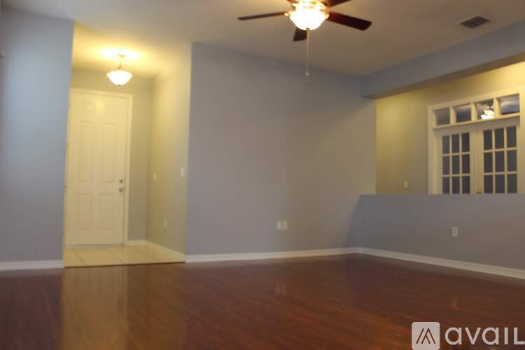 A room with a ceiling fan and a window with bars.