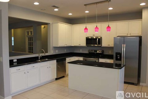 A kitchen with white cabinets and black countertops.