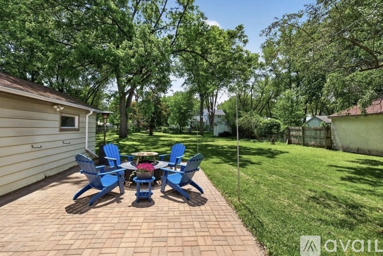 A patio with a table and chairs is surrounded by green trees.