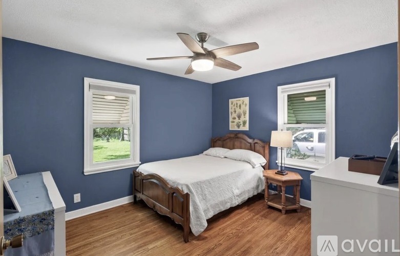 A bedroom with a bed, a nightstand, and a window.