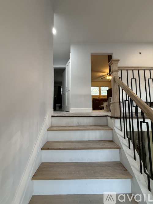 A staircase with a black railing and wooden steps leading to a room with a ceiling fan.