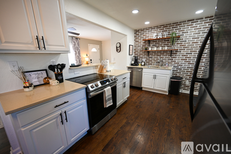 A kitchen with a black fridge and a black stove top.