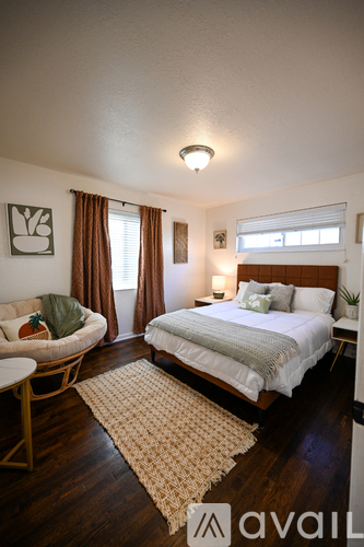 A bedroom with a bed, chair, and window.