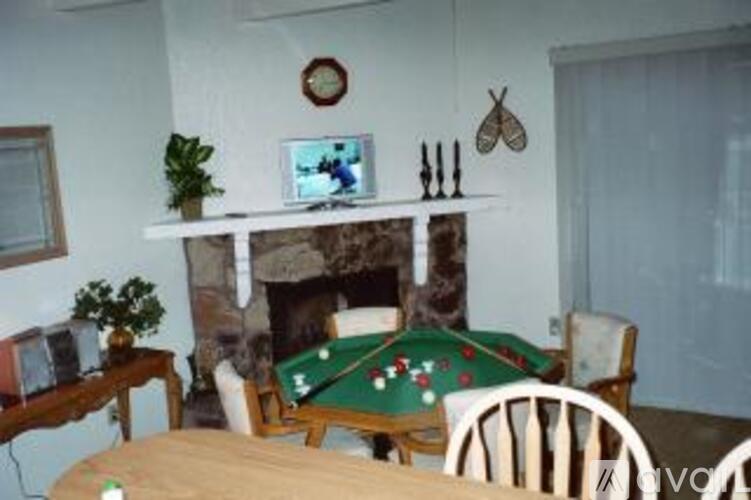 A pool table with green cloth and white balls is in the middle of the room.