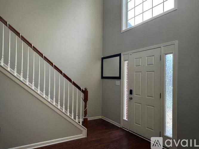 A white door is in a room with a window and a staircase.
