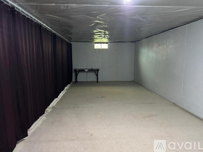 A spacious empty room with a table and chairs in the middle.