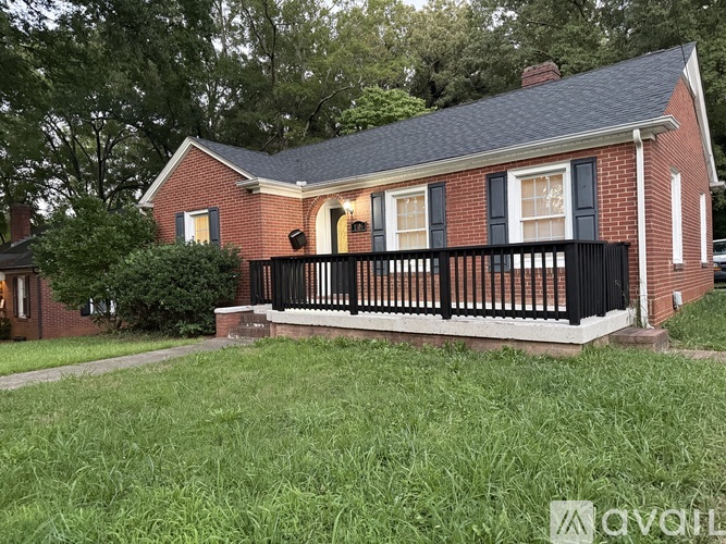 A red brick house with a black railing on the porch.