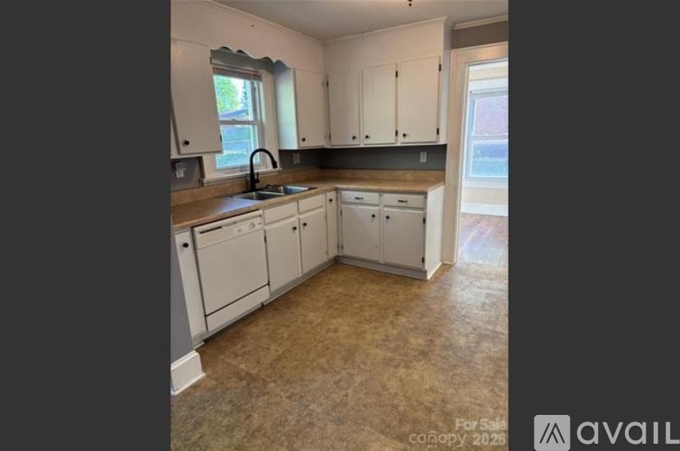 A kitchen with white cabinets and a window above the sink.