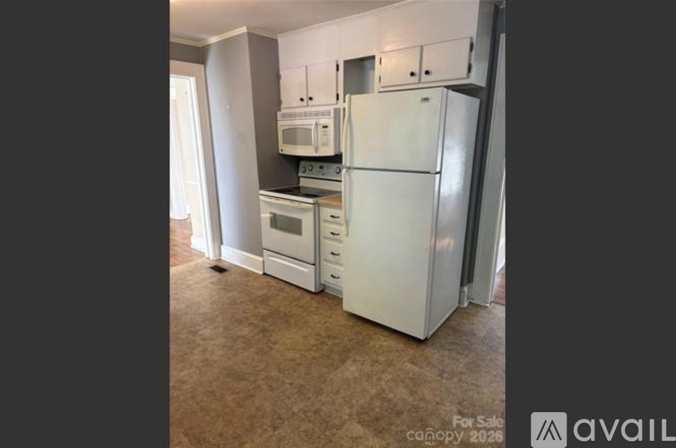 A kitchen with a white refrigerator, microwave, and oven.