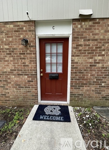 A red door with a glass panel and a welcome mat in front.