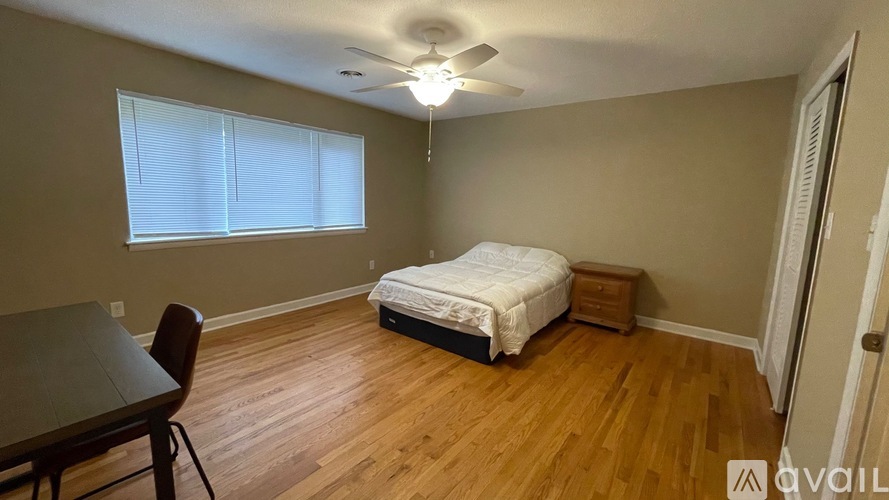 A bedroom with a bed, a table, and a chair.