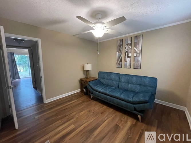 A living room with a blue couch and wooden floors.