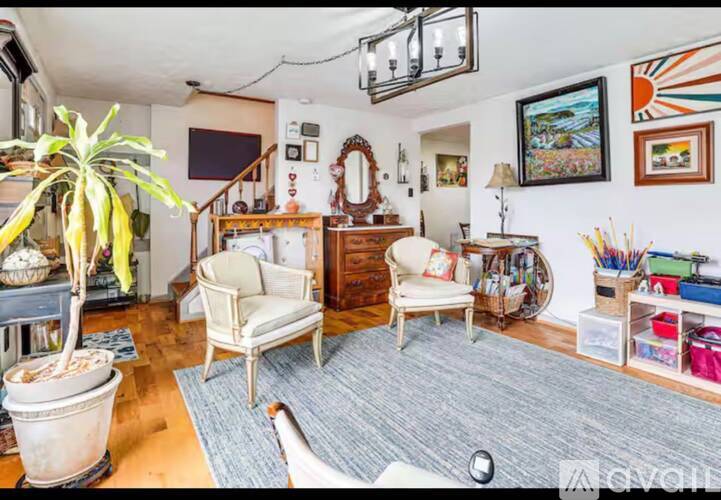 A living room with a large potted plant, two chairs, and a wooden cabinet.