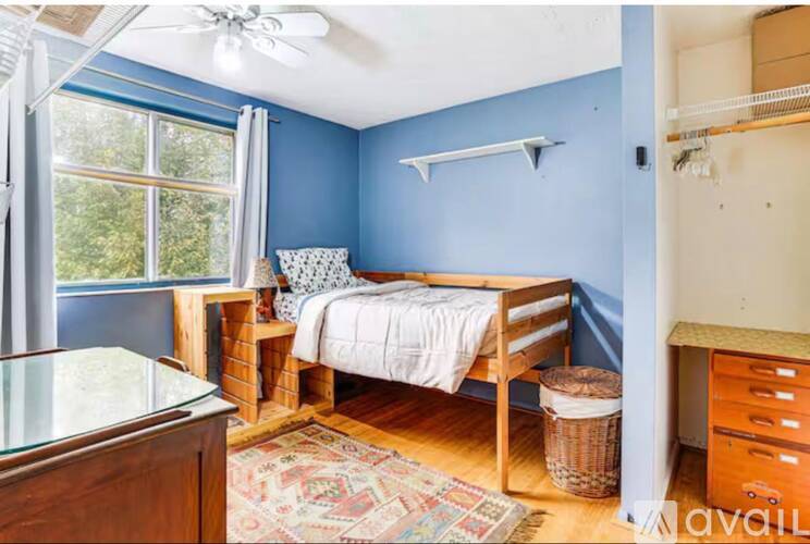 A bedroom with blue walls and a bed with a white blanket.