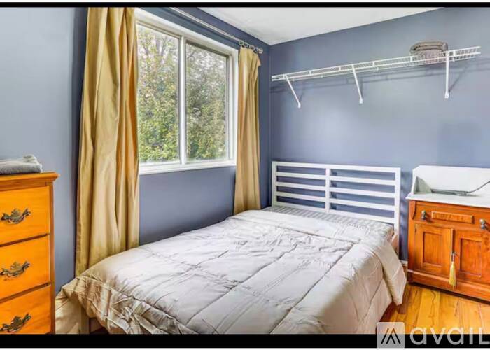 A bedroom with a bed, dresser, and window.
