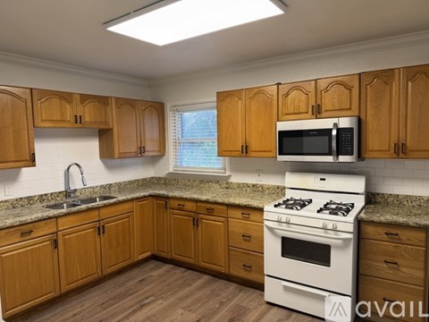 A kitchen with wooden cabinets and a white stove top oven.