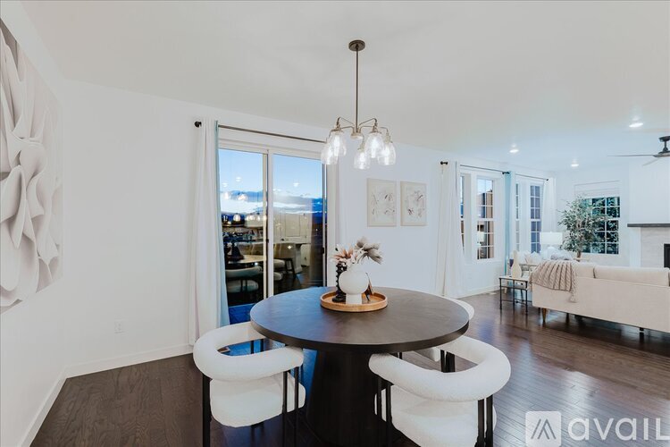 A modern dining room with a round table and white chairs.
