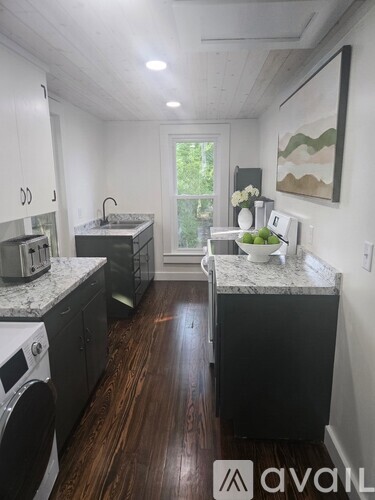 A kitchen with dark wood floors and white walls.