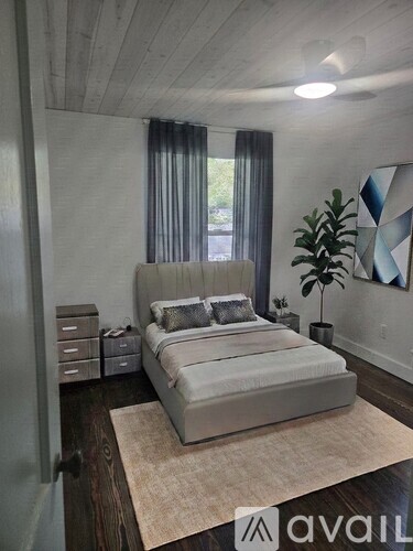 A bedroom with a large bed and a plant on the side table.