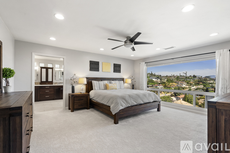 A bedroom with a large bed, a ceiling fan, and a view of the city.
