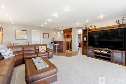 A living room with a brown leather couch and a television.