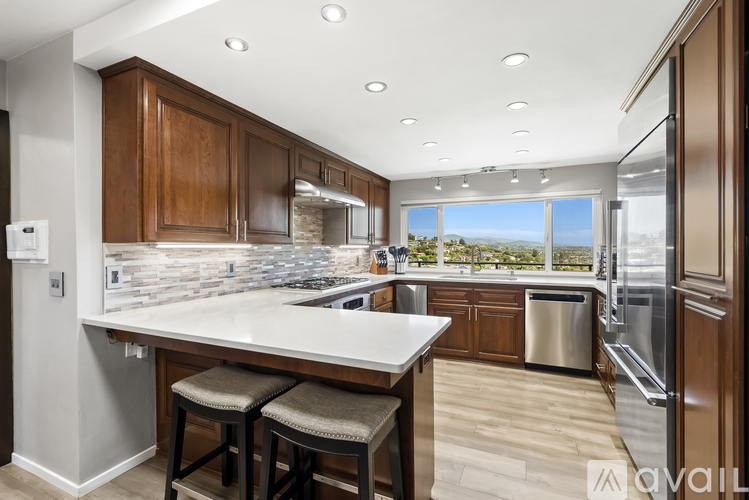 A kitchen with wooden cabinets and a large island with bar stools.