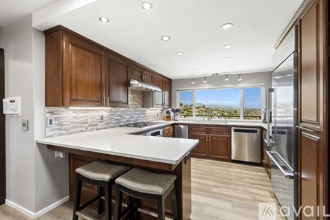 A kitchen with wooden cabinets and a large island with bar stools.